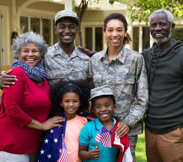 Military family with parents and children smiling outdoors on their patio space.