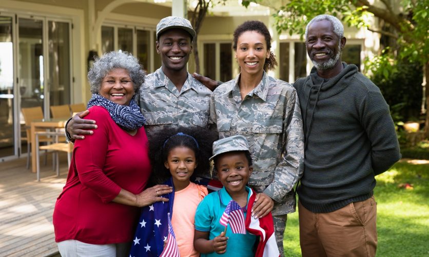 Military family with parents and children smiling outdoors on their patio space.