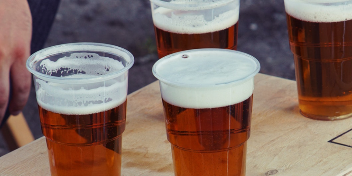 A group of clear plastic cups filled with beer.