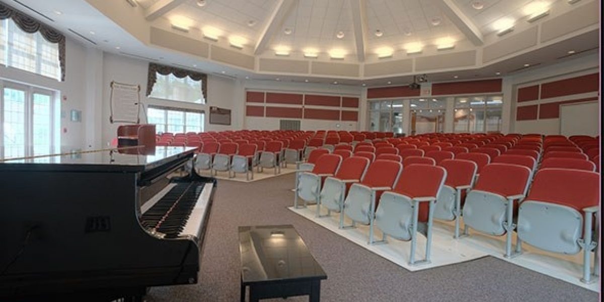 Photo of the auditorium taken from the front or stage area, with a grand piano nearby.