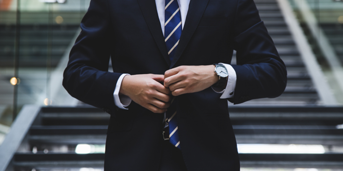 Person wearing a suit and tie, fastening the jacket closed.