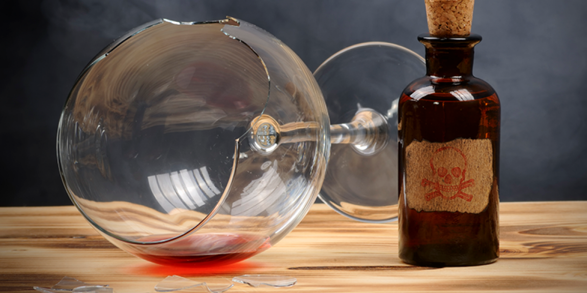 Broken wine glass on its side, next to a small apothecary bottle with a skull on the label.