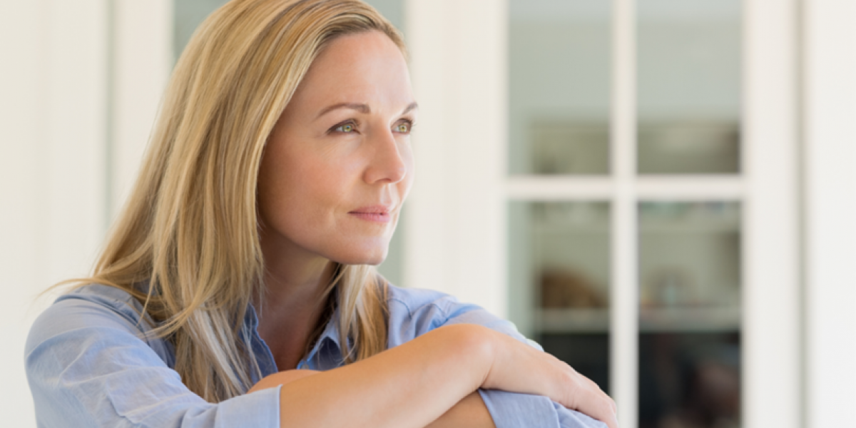 Woman with arms crossed looks thoughtfully into the distance.