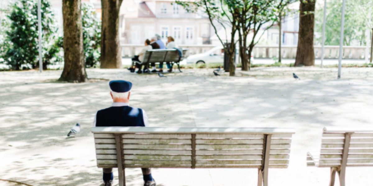 View from behind a park bench where an older man sits alone.