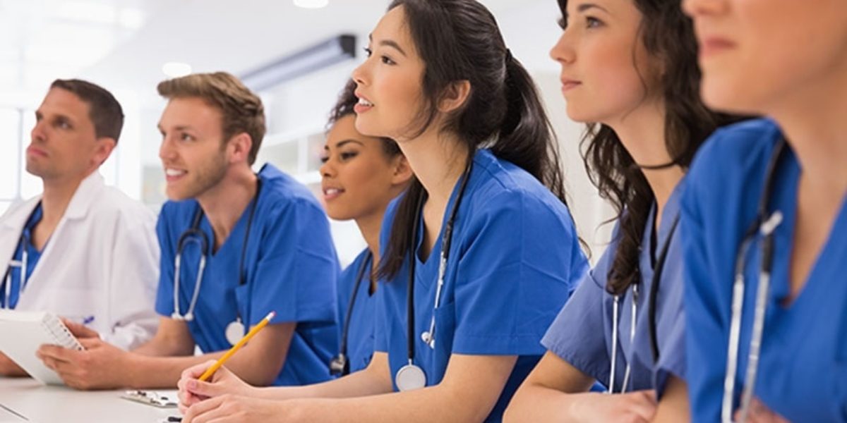 Group of young people in scrubs, sitting in class.