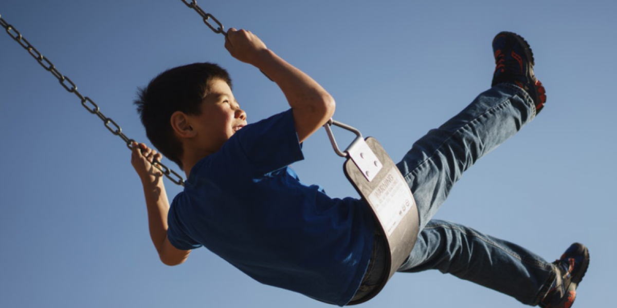 Young boy swinging on a swing and smiling.