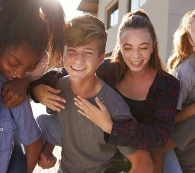 A group of teen boys and girls in a group smiling.