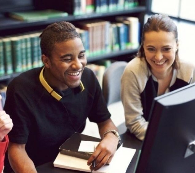 A teen sitting in front of a computer screen with two adults.