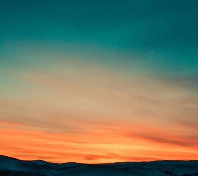 A bright and vibrant sunset overlooking the peaks of mountains.