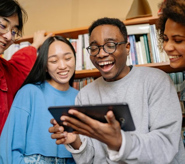 Diverse group smiling while looking at a tablet computer.
