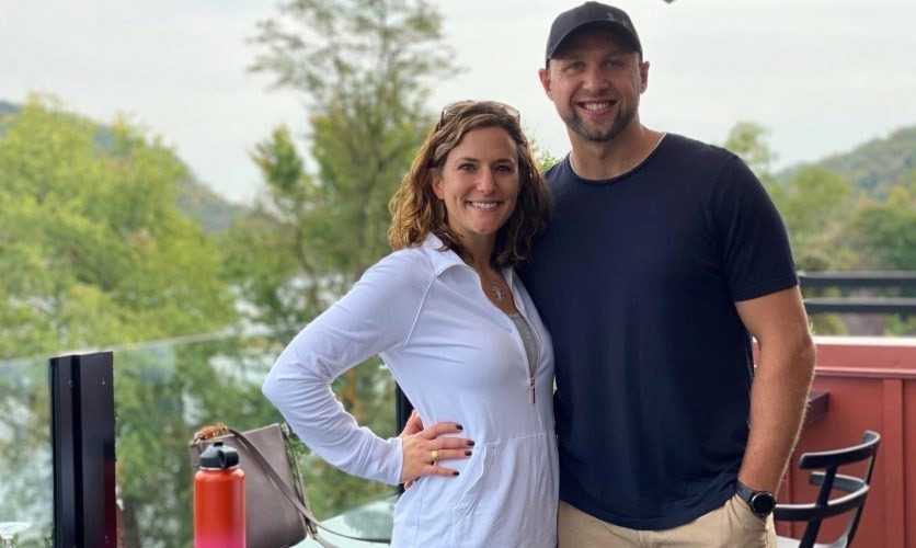 A couple hugging and looking happy at an outdoor restaurant.