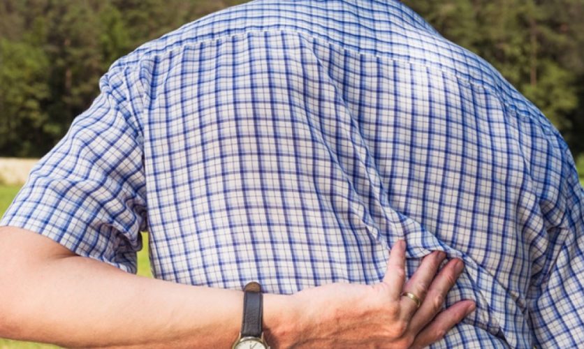 View from behind of a person gripping their back in pain.