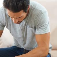 Man in t-shirt looking sadly at the floor